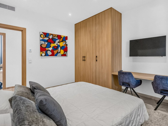 Bedroom in a modern villa with bed, desk and wall-mounted television