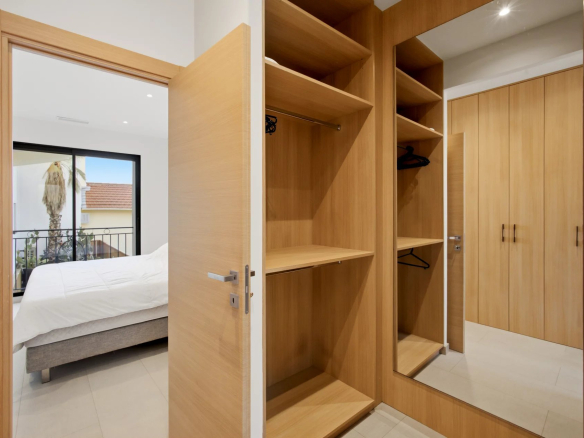 Interior of a bedroom with a wooden wardrobe and mirror, overlooking a bed and a terrace.