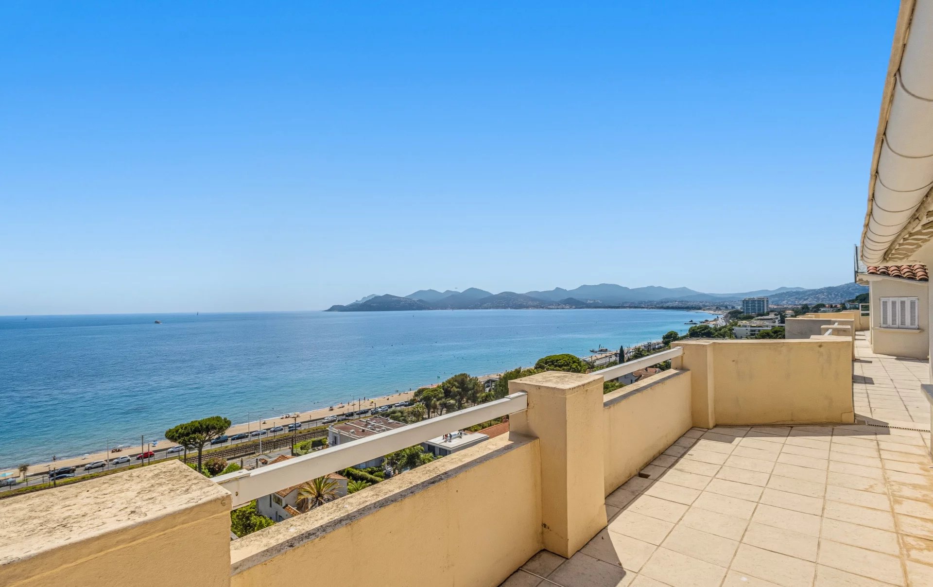 Terrasse avec vue sur la mer à Cannes Vue panoramique sur la mer depuis une terrasse à Cannes, avec des montagnes en arrière-plan.