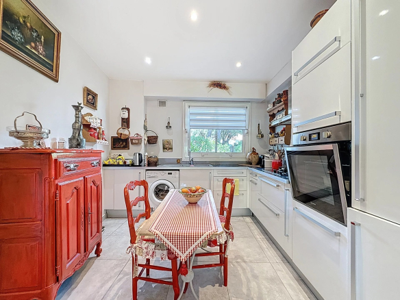 Cuisine moderne avec mobilier rouge et table à manger, éclairée par la lumière naturelle.
