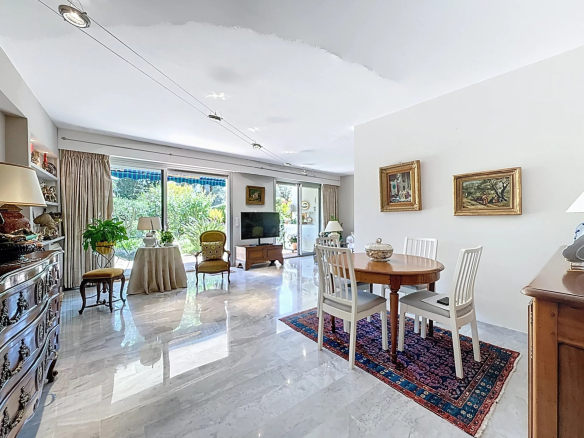 Intérieur d'un appartement lumineux avec salon, salle à manger et accès à un jardin privatif.