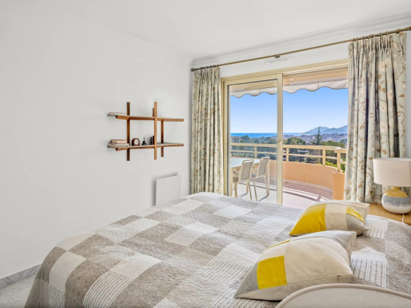 Room with bed and sea view, balcony and modern furniture.