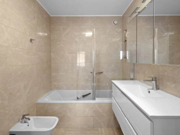 Modern bathroom with bathtub and shower, beige tiles.