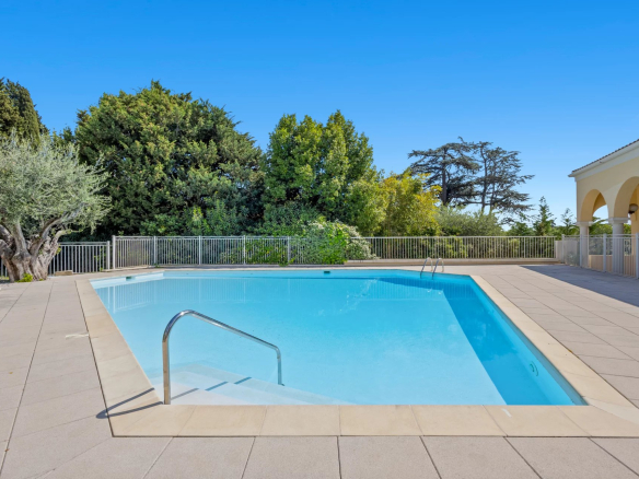 Piscine d'une résidence sécurisée à Cannes, entourée de verdure.