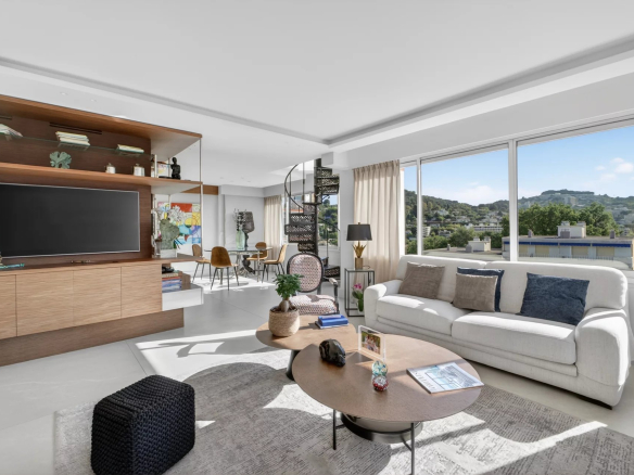 Intérieur d'un appartement moderne avec salon lumineux et vue sur la nature.