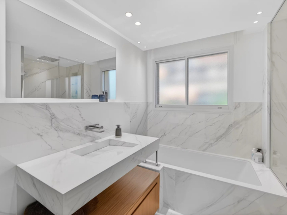 Salle de bain moderne avec baignoire et lavabo en marbre.