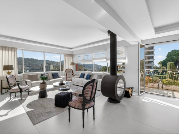 Intérieur d'un appartement moderne avec salon lumineux et cheminée, vue sur la terrasse.