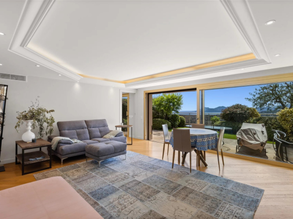 Intérieur d'un appartement avec vue sur la mer, salon lumineux et terrasse.