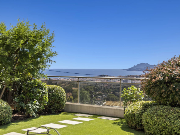 Vue panoramique sur la mer depuis une terrasse avec jardin, entourée de verdure.