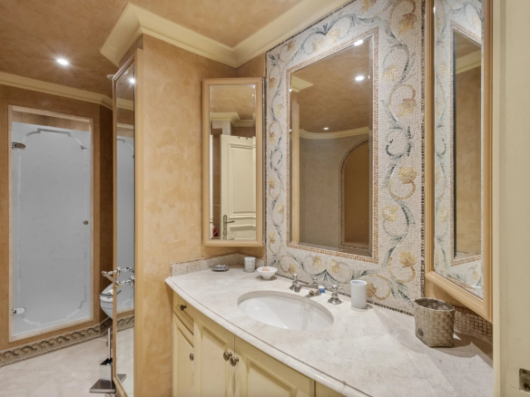 Salle de bain d'un appartement avec lavabo et miroir, décorée de mosaïque.