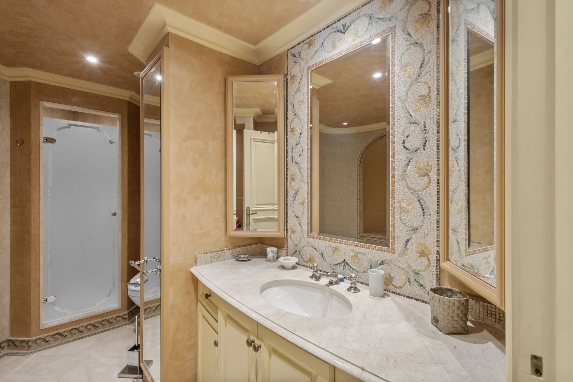 Salle de bain d'un appartement avec lavabo et miroir, décorée de mosaïque.