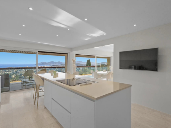 Interior of a modern apartment with open kitchen and panoramic views of the sea and mountains.