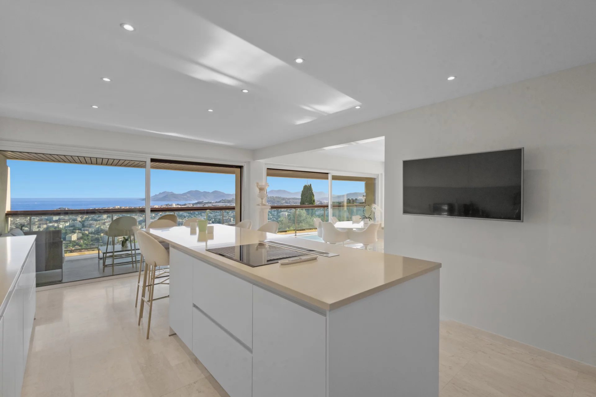 Interior of a modern apartment with open kitchen and panoramic views of the sea and mountains.