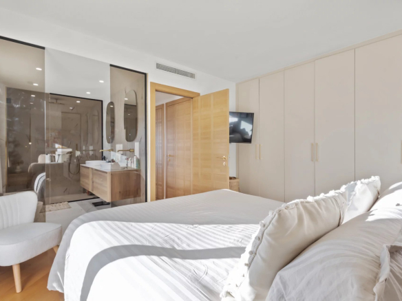 Bedroom in a renovated apartment with bed, wardrobe and bathroom visible in the background.