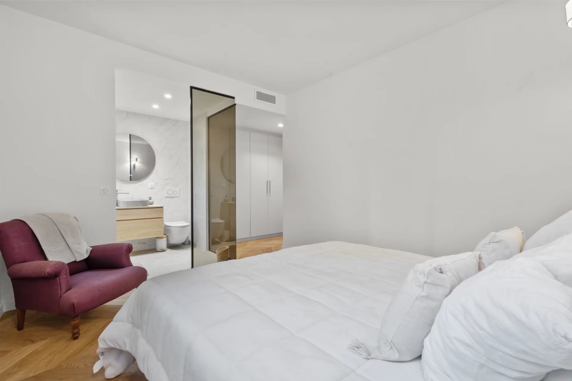 Renovated apartment room in Le Cannet Room in a renovated apartment with a bed and an armchair, overlooking a modern bathroom.