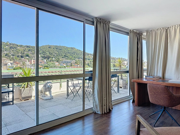 Interior view of a duplex in Le Cannet with windows overlooking a terrace and a green landscape.