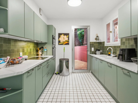 Cuisine moderne et spacieuse d'une villa rénovée au Cannet, avec carrelage blanc et meubles verts.