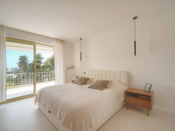 Chambre d'un appartement rénové au Cannet, avec lit double et accès à une terrasse ensoleillée.