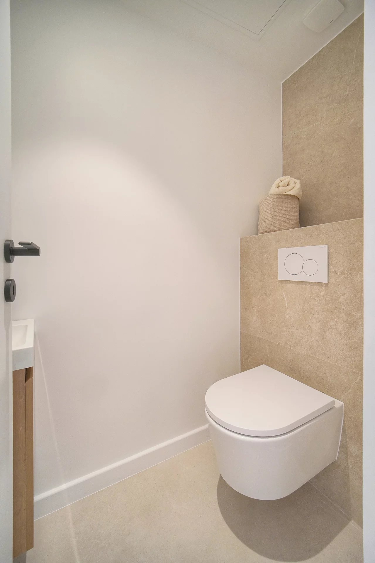 Toilettes modernes dans un appartement Toilettes modernes avec carrelage beige et mur blanc dans un appartement rénové.