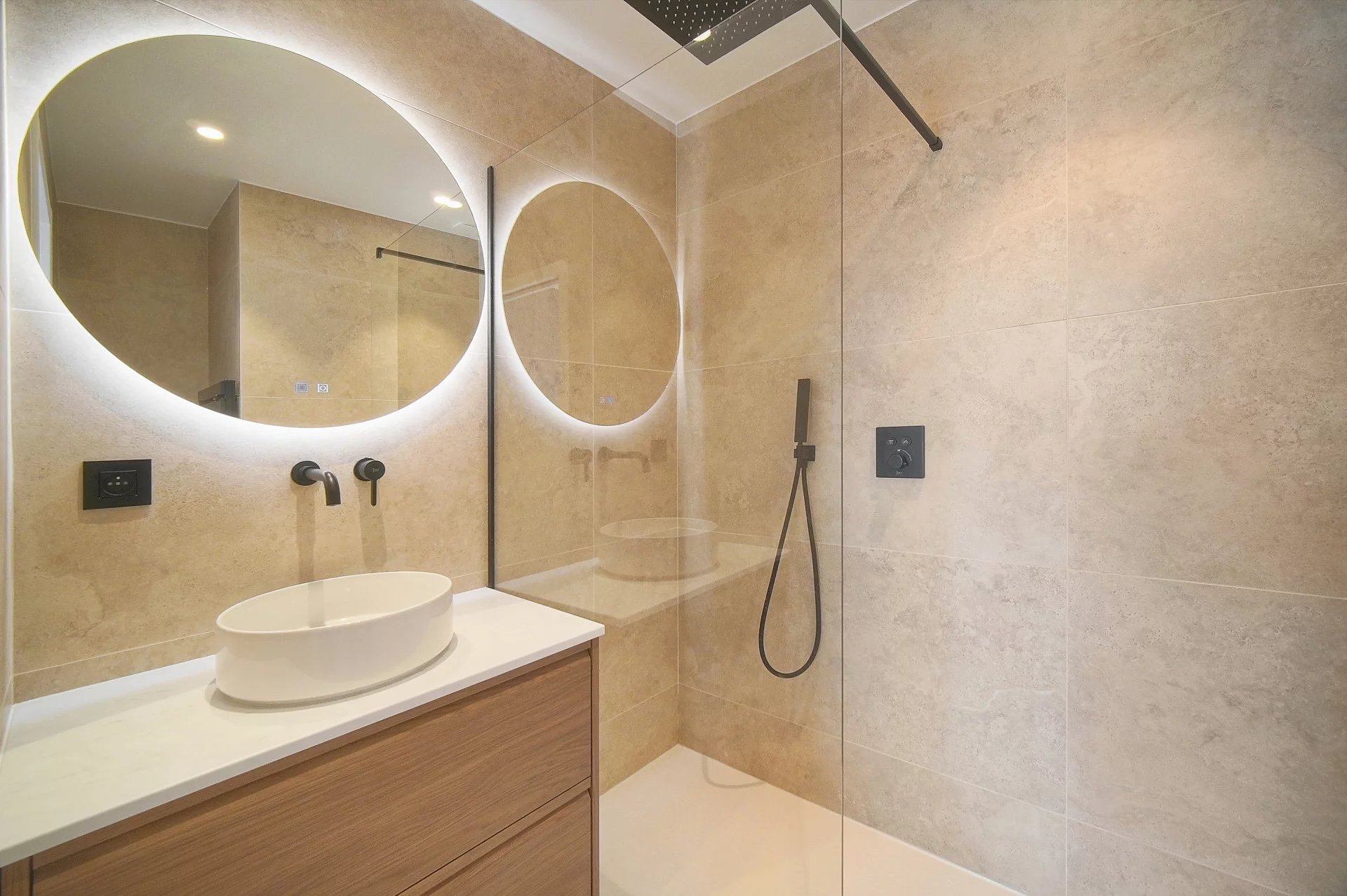 Salle de bain rénovée Salle de bain moderne avec douche à l'italienne et miroir rond lumineux.