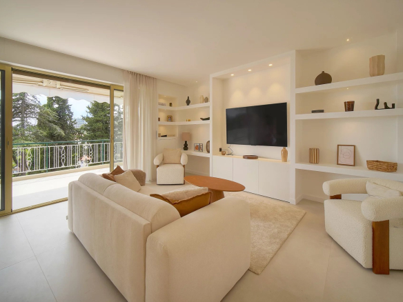 Salon lumineux d'un appartement rénové avec accès à une terrasse ensoleillée et vue sur la verdure.