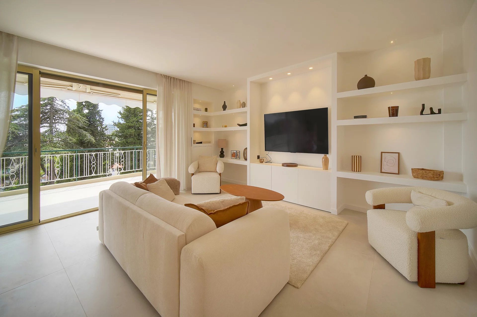 Salon d’un appartement au Cannet Salon lumineux d'un appartement rénové avec accès à une terrasse ensoleillée et vue sur la verdure.
