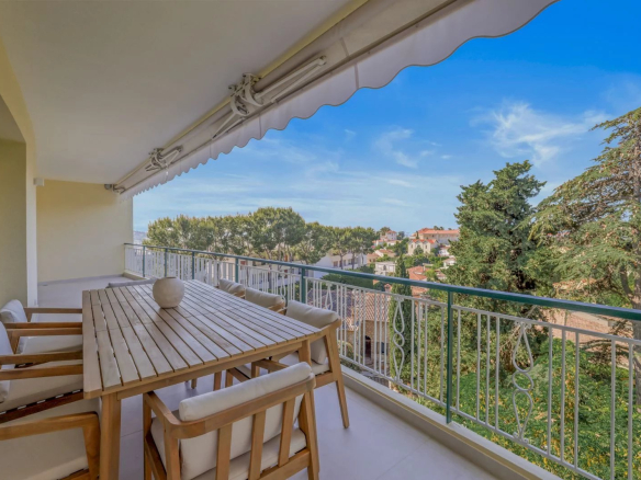 Terrasse ensoleillée d'un appartement au Cannet avec vue sur la verdure.