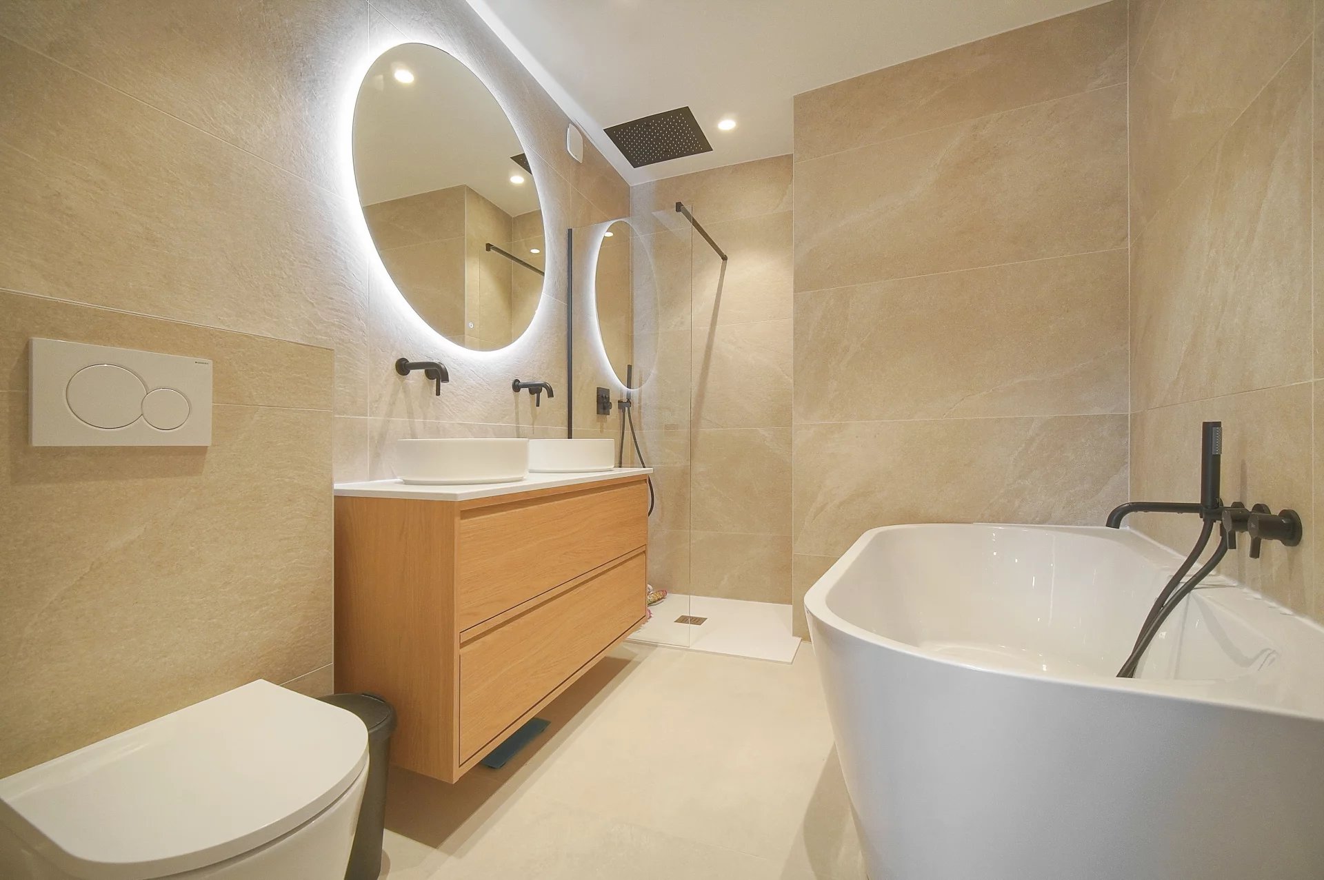 Salle de bain rénovée Salle de bain moderne avec baignoire, douche et double vasque en bois.