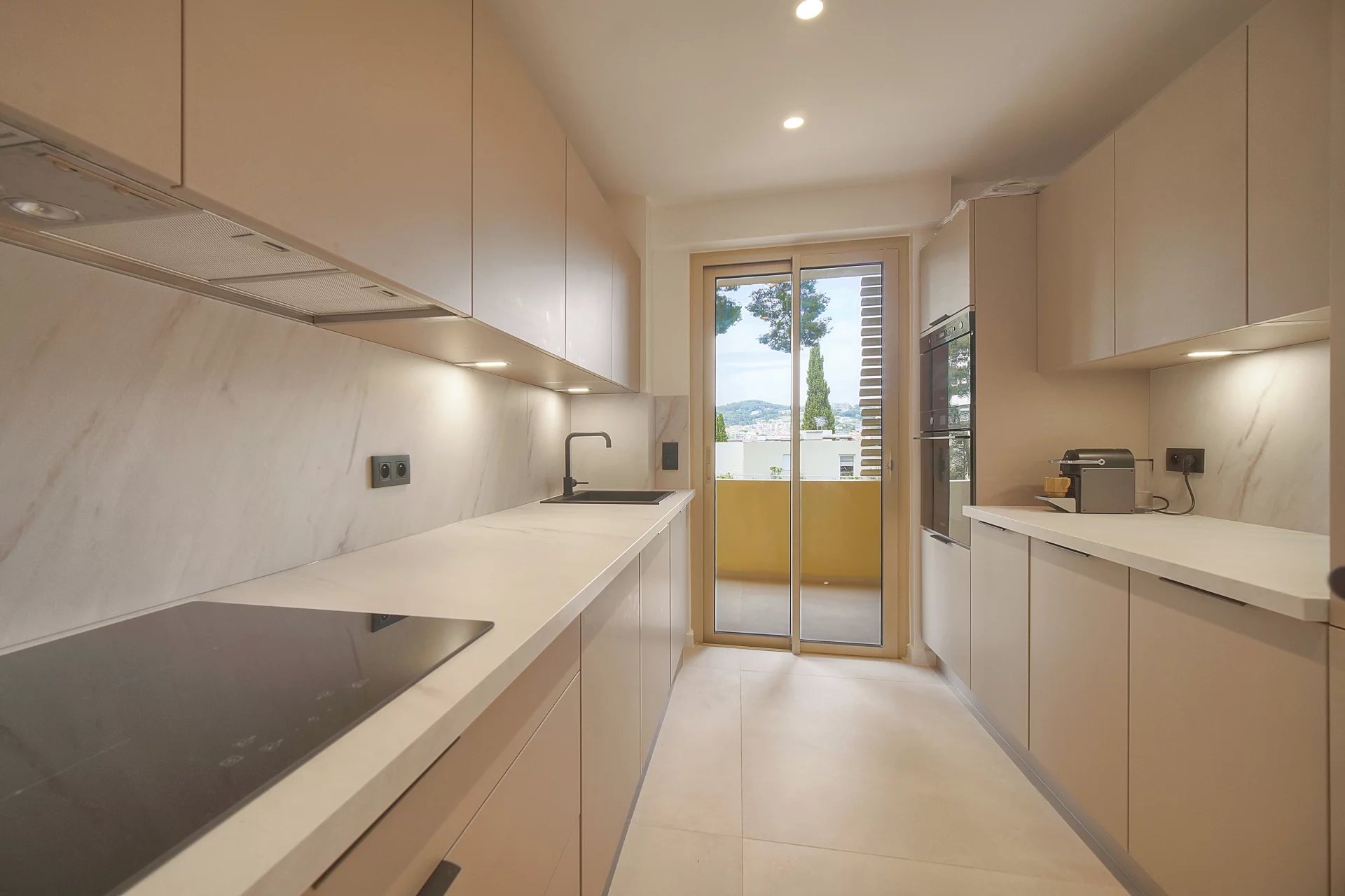 Cuisine d’un appartement au Cannet Cuisine moderne d'un appartement rénové au Cannet, avec accès à un balcon.