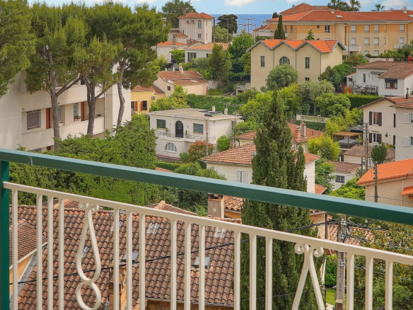 Vue depuis un balcon d'un appartement au Cannet, avec des maisons et de la verdure en arrière-plan.