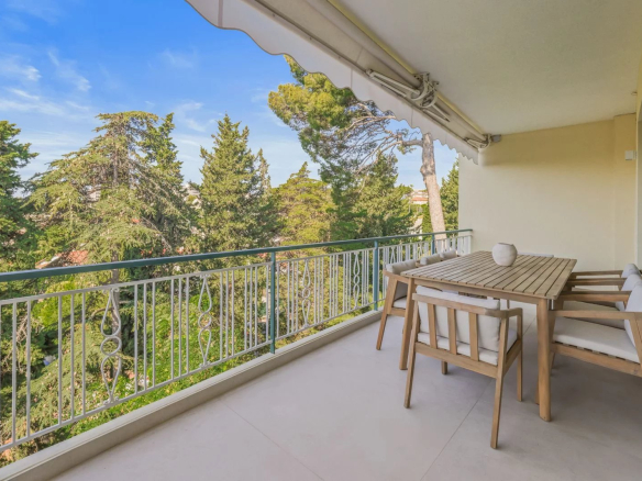 Terrasse d'un appartement au Cannet avec vue sur la verdure, mobilier en bois.