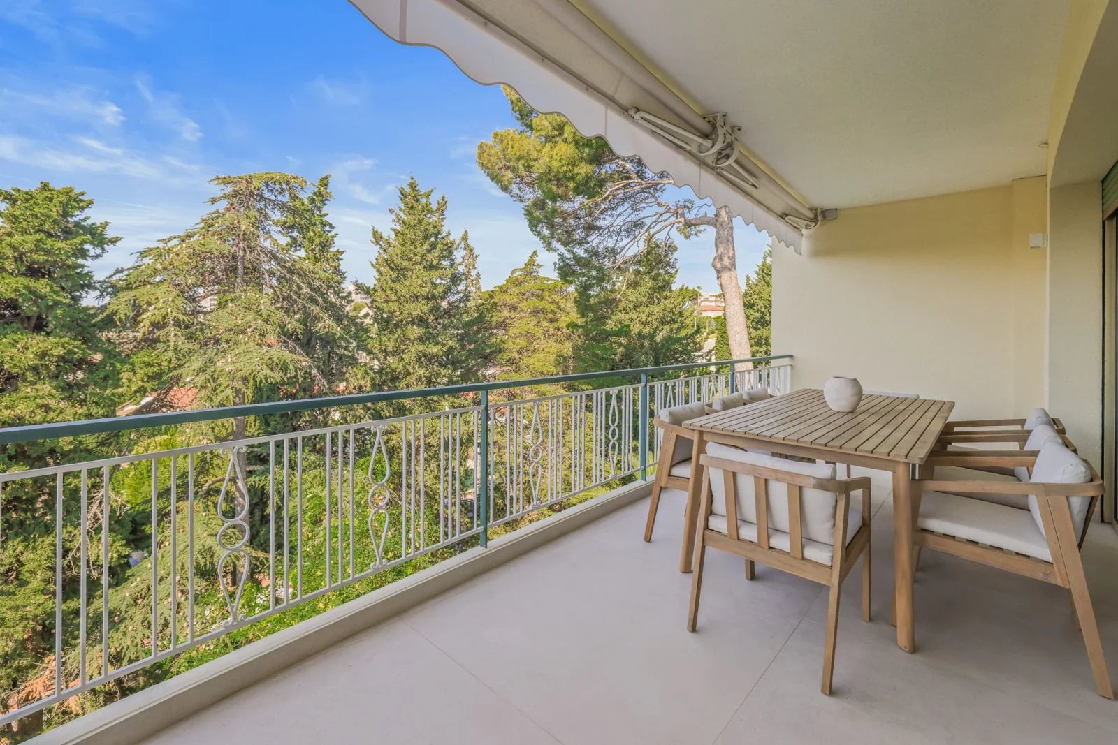 Terrasse ensoleillée au Cannet Terrasse d'un appartement au Cannet avec vue sur la verdure, mobilier en bois.