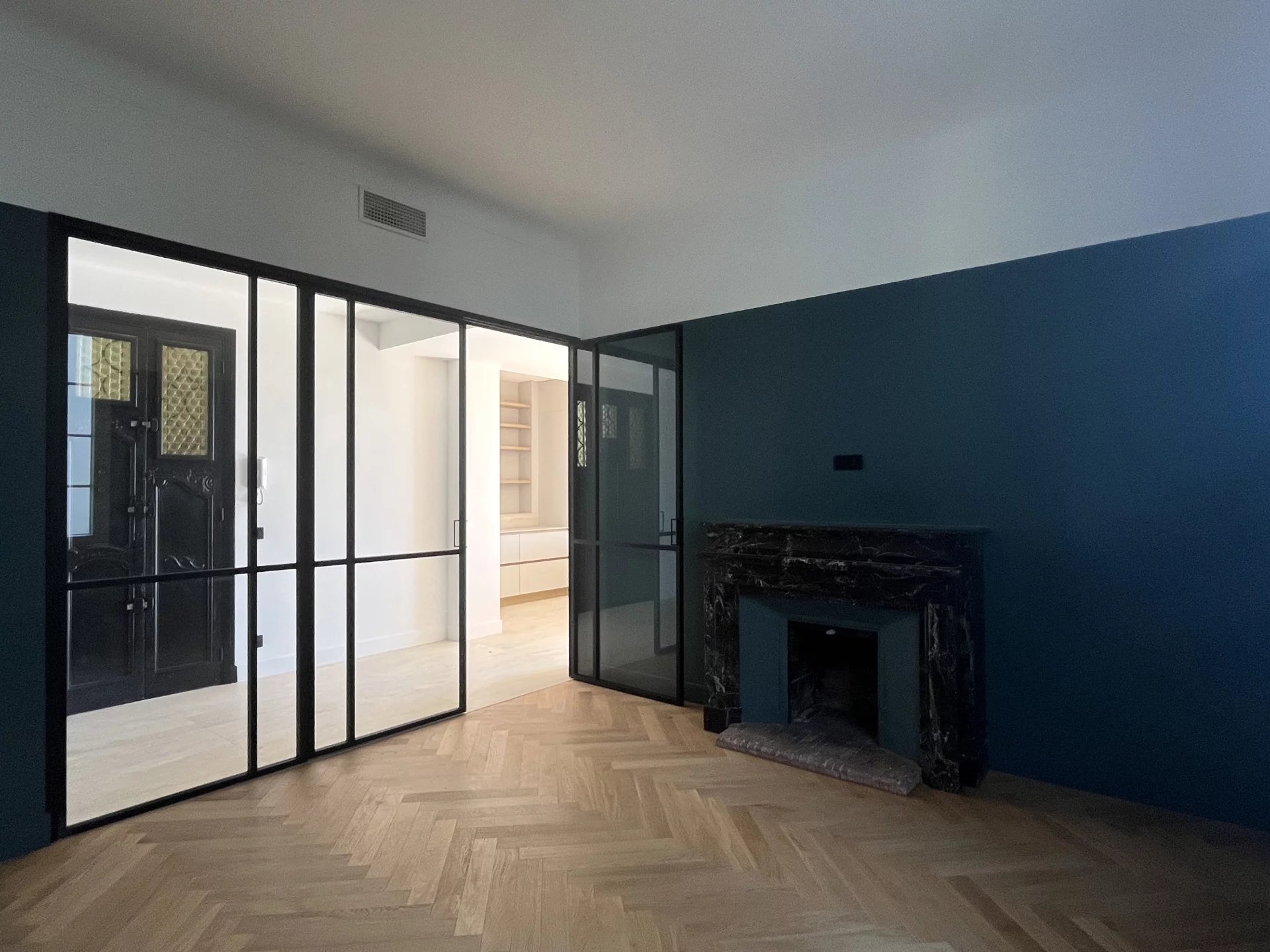Intérieur d’un appartement rénové au Cannet Intérieur d'un appartement rénové avec des murs verts et un sol en parquet, cheminée en marbre visible.