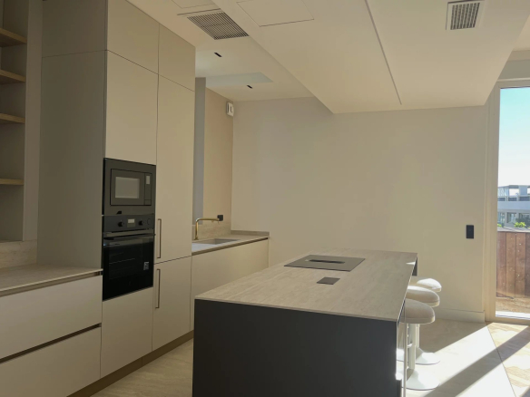 Cuisine moderne d'un appartement rénové avec îlot central et équipements haut de gamme.