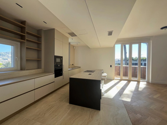 Cuisine moderne et spacieuse d'un appartement rénové au Cannet, avec îlot central et lumière naturelle.