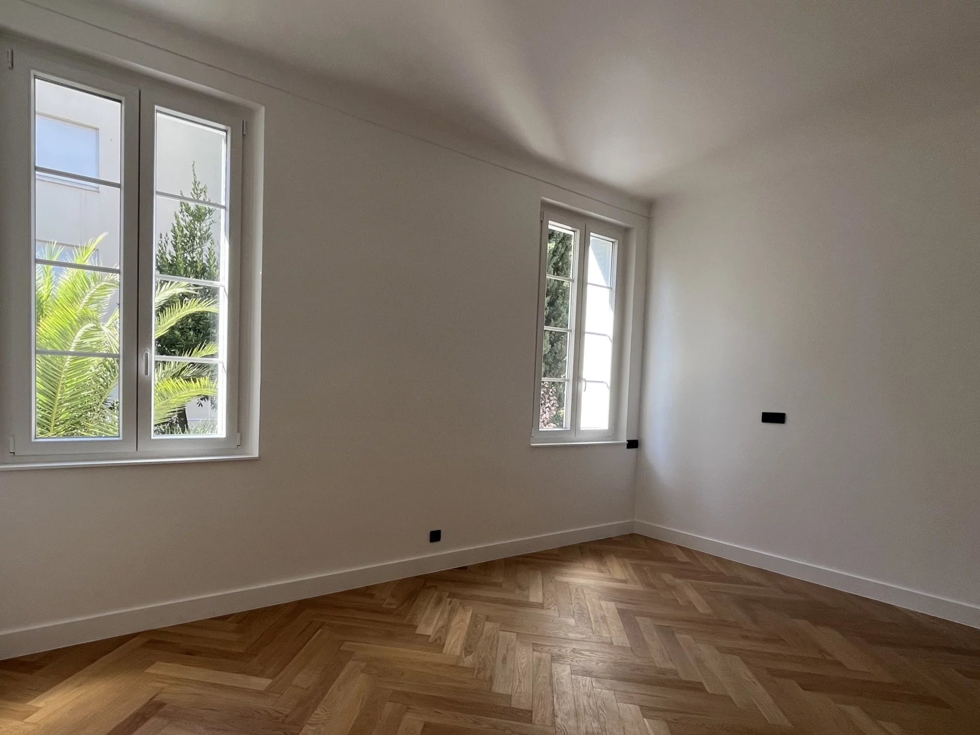 Appartement rénové au Cannet Intérieur d'un appartement rénové avec parquet en chevron et grandes fenêtres au Cannet.