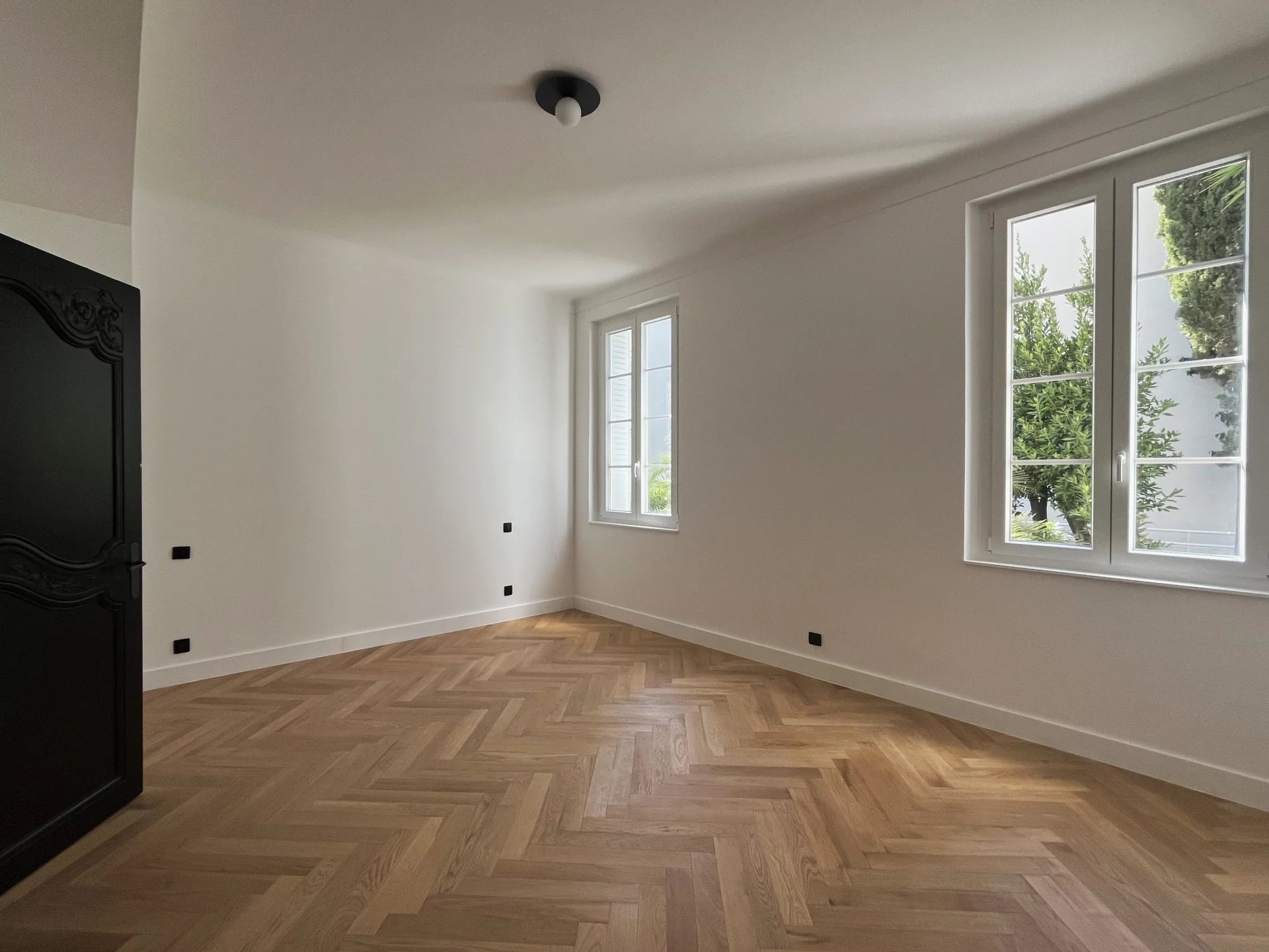 Appartement rénové au Cannet Intérieur d'un appartement rénové avec parquet en bois et fenêtres lumineuses.
