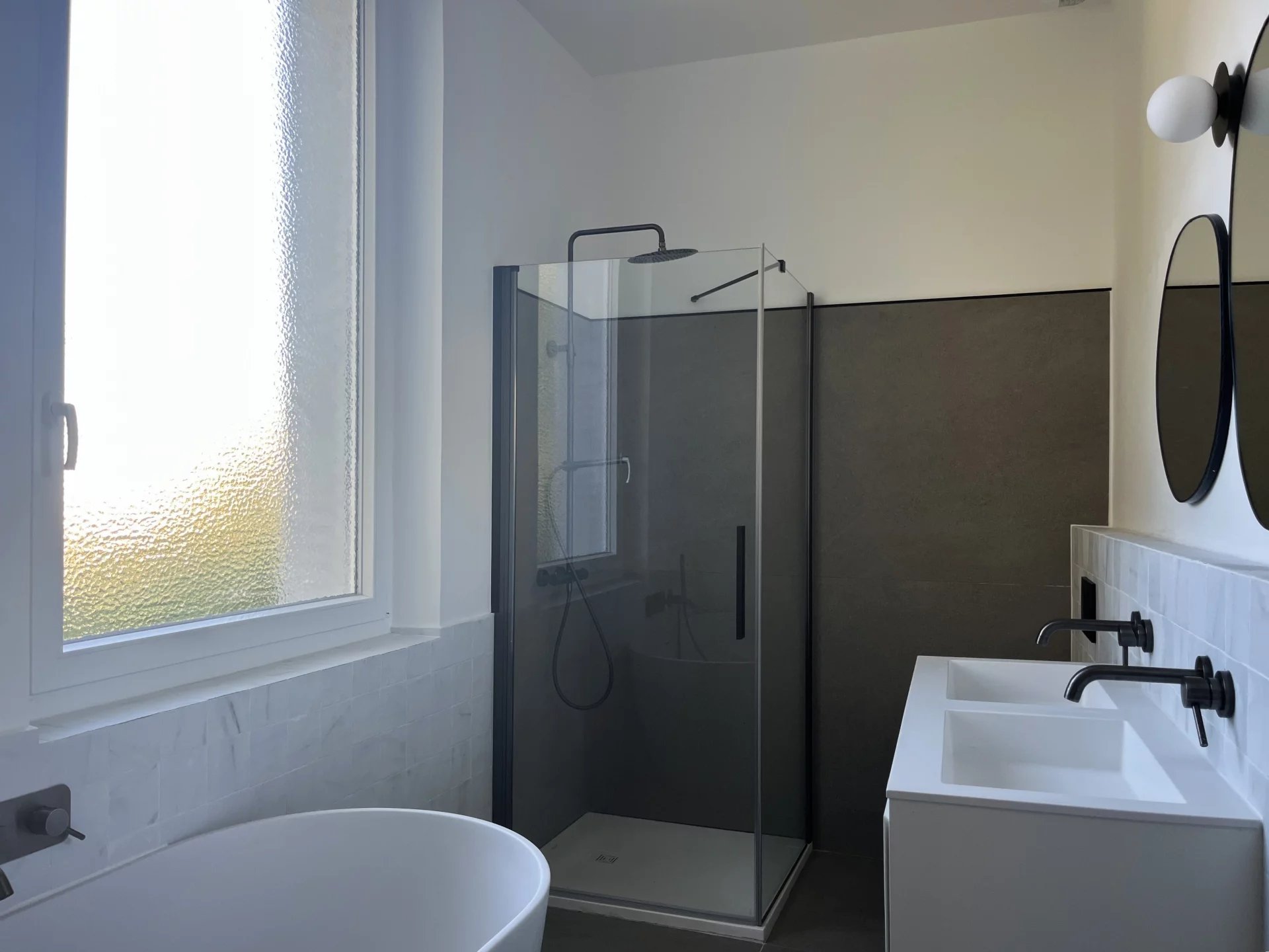 Salle de bain rénovée Salle de bain moderne avec douche en verre, baignoire et double vasque.