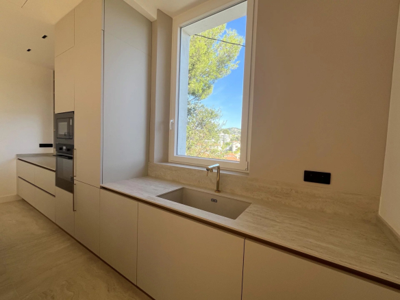 Cuisine moderne d'un appartement rénové avec un évier et une fenêtre donnant sur l'extérieur.