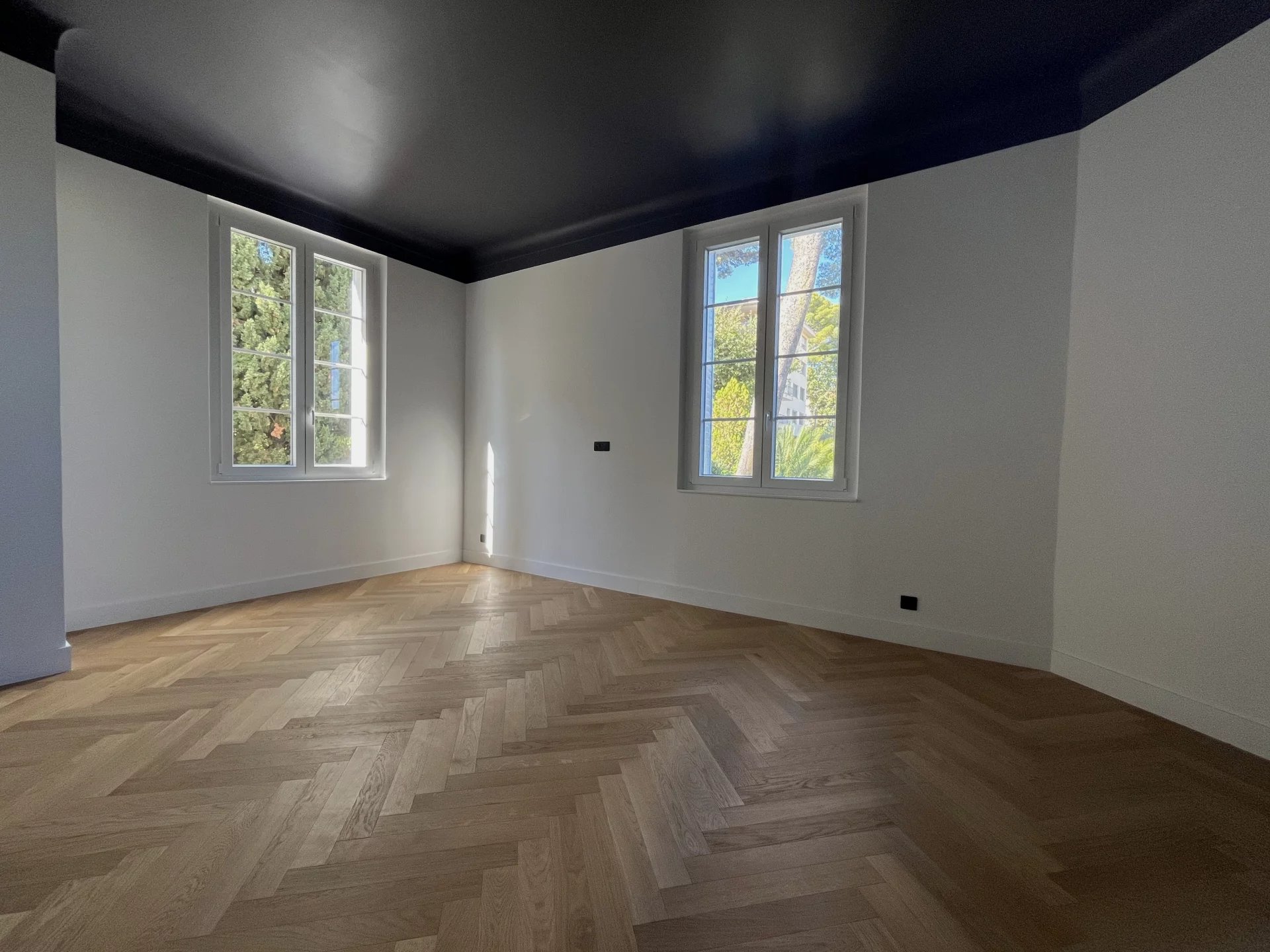 Appartement rénové au Cannet Intérieur d'un appartement rénové avec parquet en bois et fenêtres lumineuses.