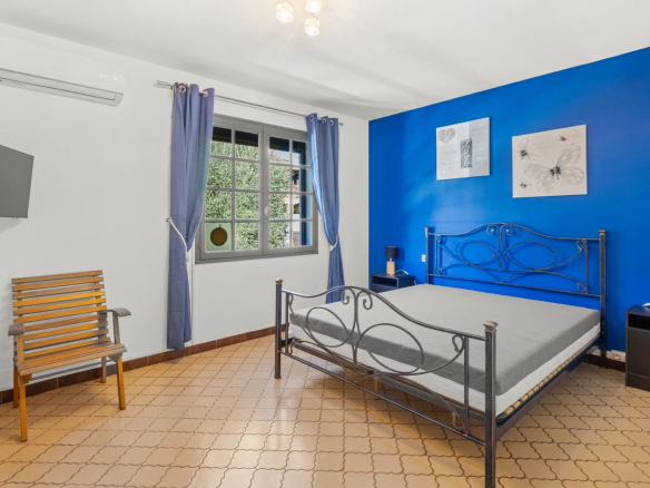 Bedroom in a villa in Mougins with blue wall, iron bed and modern furniture.