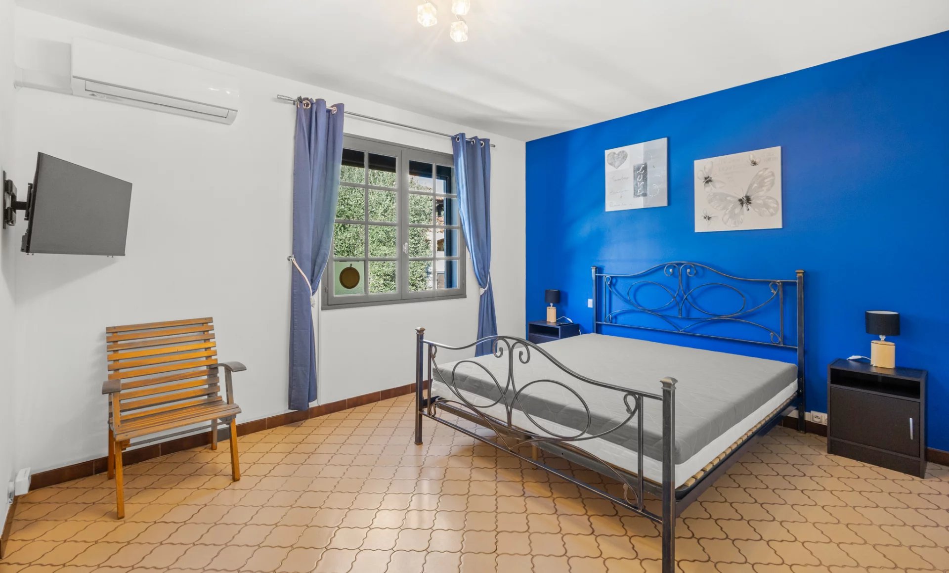 Bedroom in a villa in Mougins with blue wall, iron bed and modern furniture.