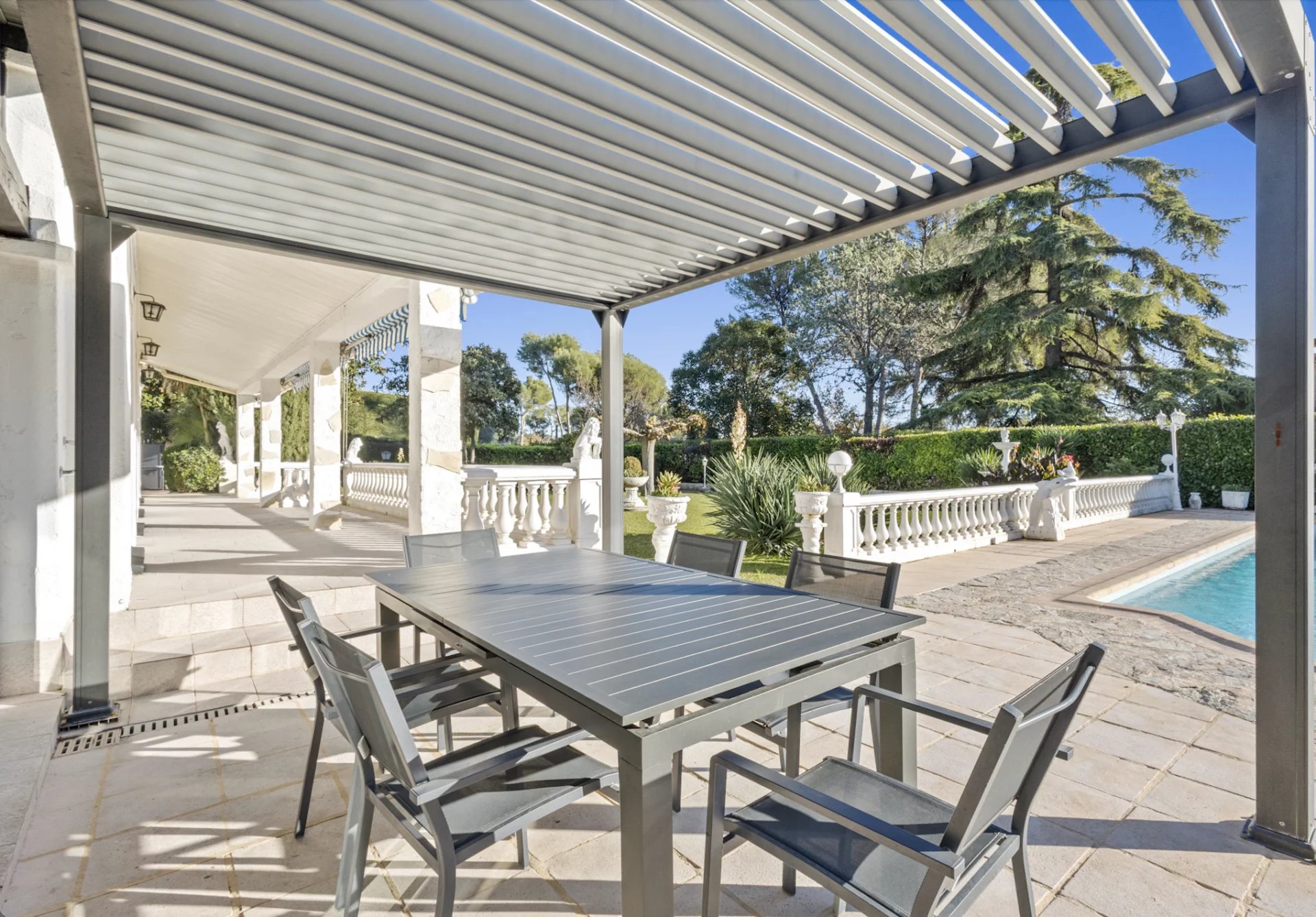 Terrace with table and chairs, swimming pool and landscaped garden in Mougins.