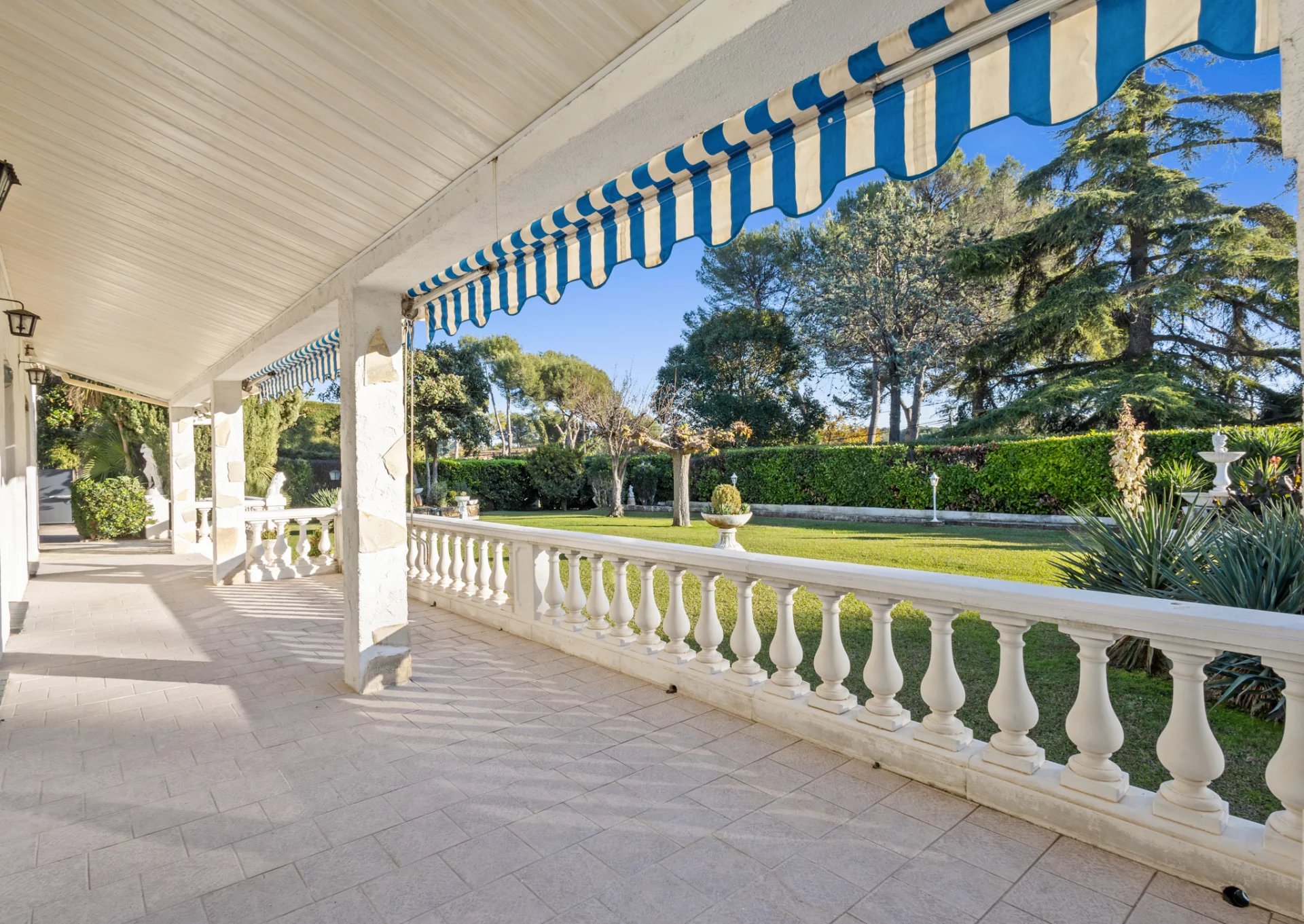 Terrace of a Provençal villa in Mougins with balustrade and landscaped garden in the background.