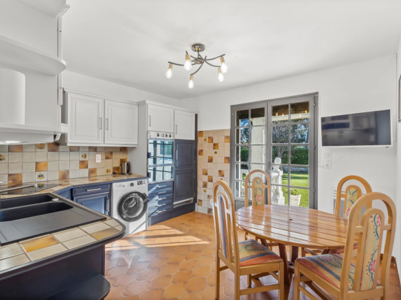Kitchen of a Provençal villa in Mougins, with table and chairs, window overlooking the garden.