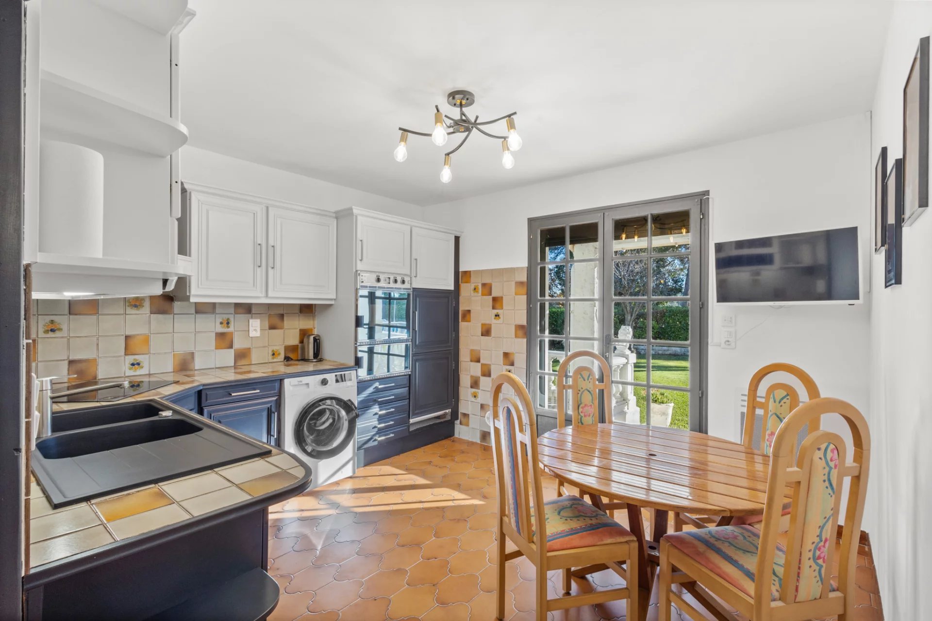 Kitchen of a Provençal villa in Mougins, with table and chairs, window overlooking the garden.