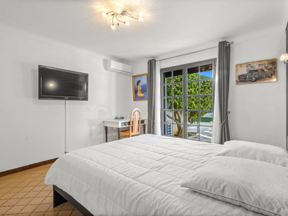 Room in a villa in Mougins with double bed, television and window overlooking the outside.