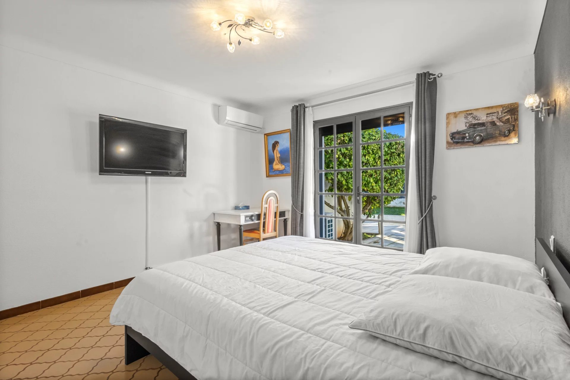 Room in a villa in Mougins with double bed, television and window overlooking the outside.