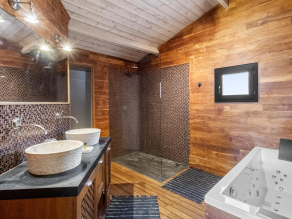 Modern bathroom with double sink, walk-in shower and bathtub, wood decor.