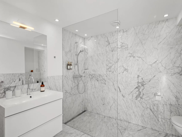 Modern bathroom with marble shower and vanity unit.